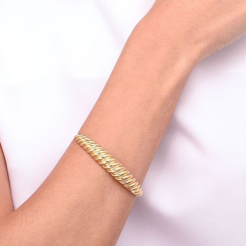 Pulso de uma pessoa usando uma pulseira dourada com elos arredondados.