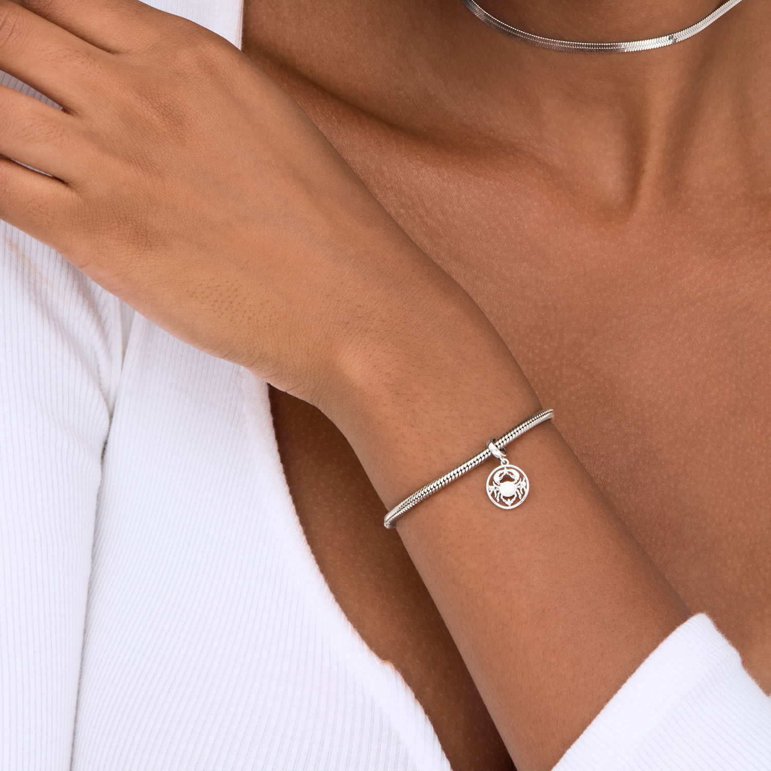 Pulsera de prata com pingente de rosto sorridente e estrela, usada no pulso de uma mulher.