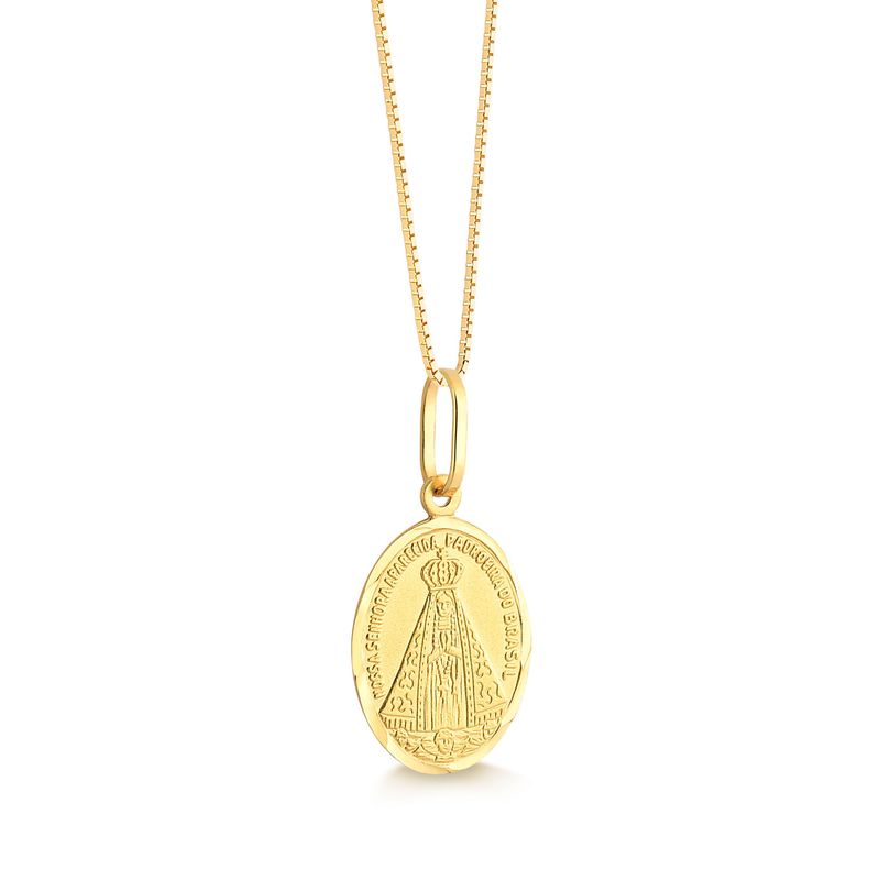 Colar com pingente dourado oval com imagem e texto religioso, incluindo uma cabeça de Nossa Senhora Aparecida com coroa.