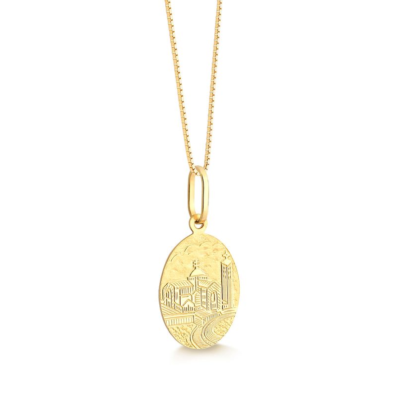 Colar dourado com pingente oval de cidade com prédio, torre e ponte, suspenso por corrente dourada.
