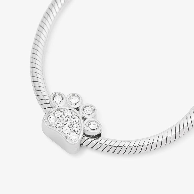Pulseira de metal prateado com elo em espiral e pingente em forma de coração com cristais transparentes.