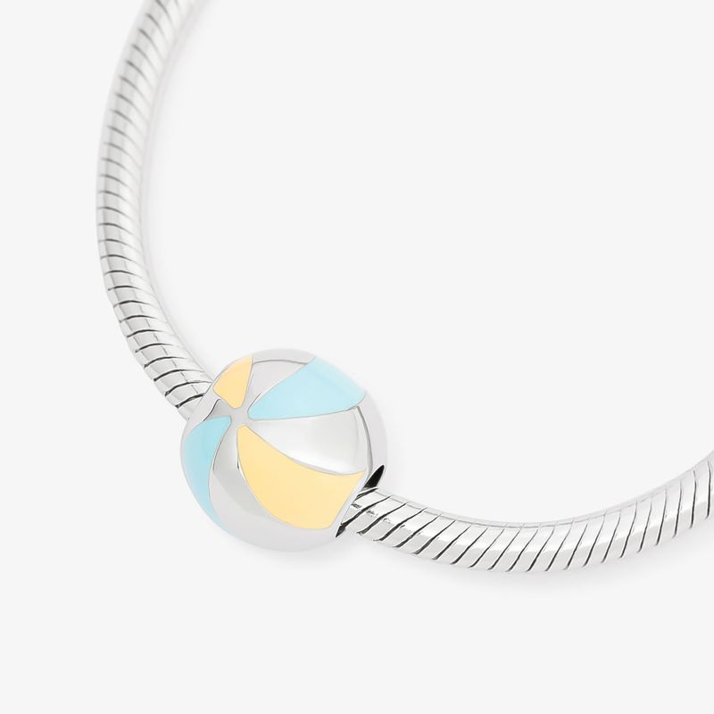 Pingente de prata com detalhes em azul e amarelo em forma de esfera, parte de uma pulseira de corrente prateada.
