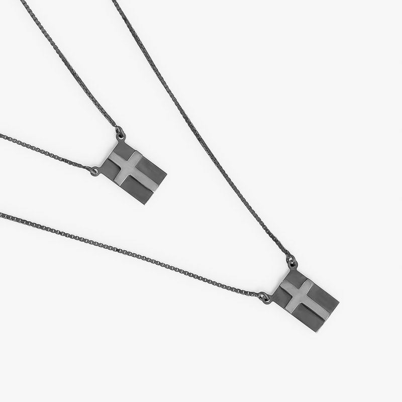 Colares de prata com pingentes de cruz, com correntes finas e retas, em fundo branco.