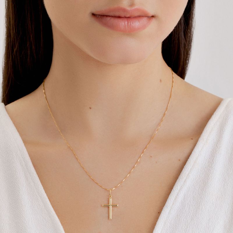 Colar de corrente fina dourada com pingente de cruz.