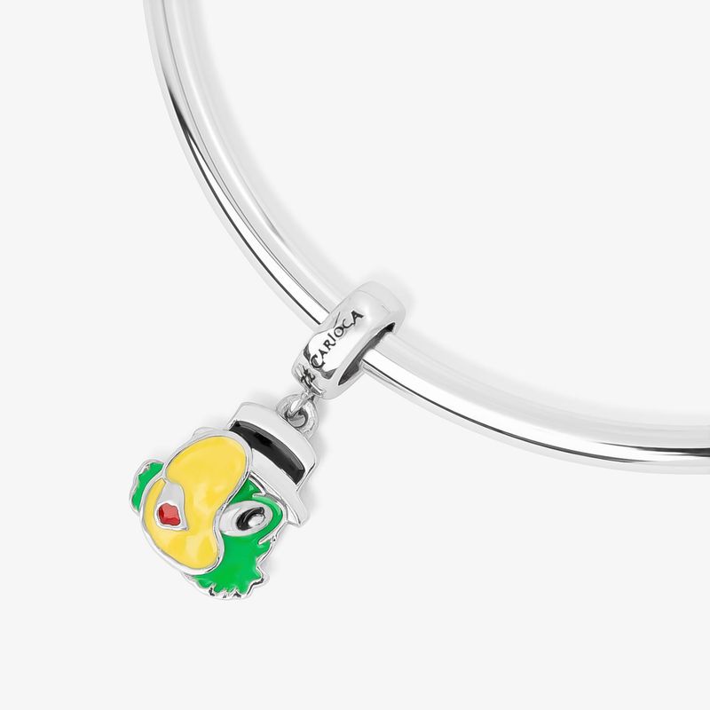 Pingente de desenho animado de uma tartaruga com cores amarelo, verde, preto, branco e vermelho, preso a uma corrente de prata.