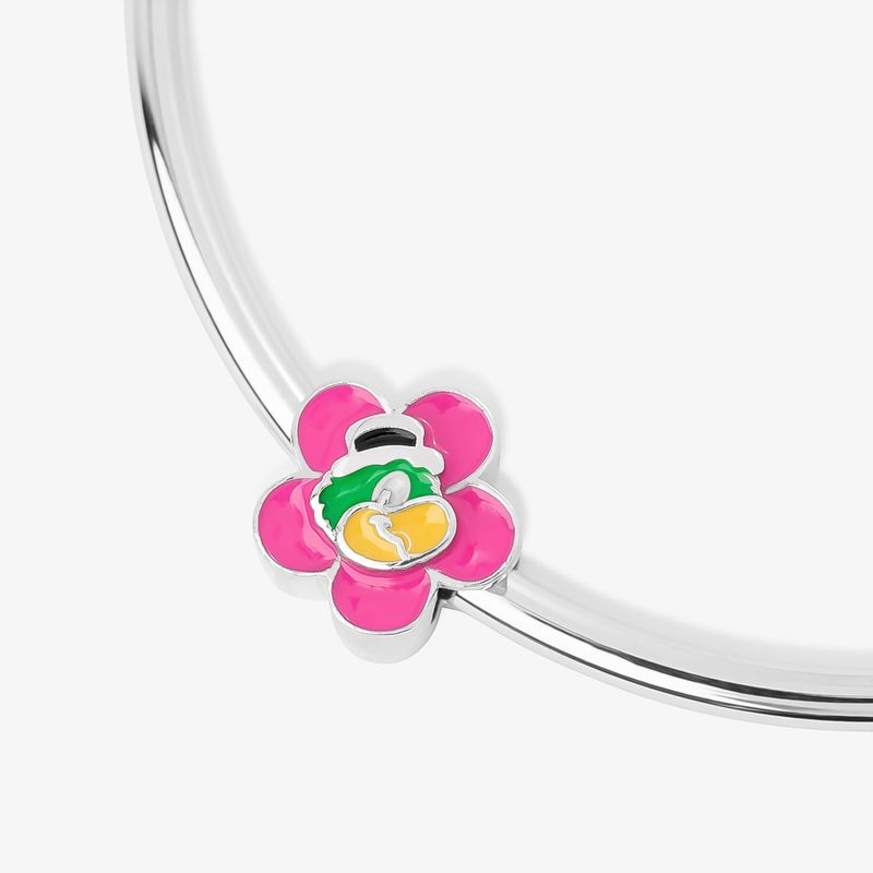 Pingente de flor rosa com personagem verde, amarelo e preto, preso em uma corrente prateada, sobre uma superfície branca.
