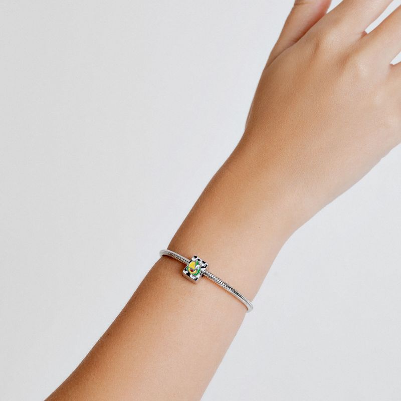 Pulso com pulseira de prata com pingente colorido e detalhe de cristais, sobre fundo branco.