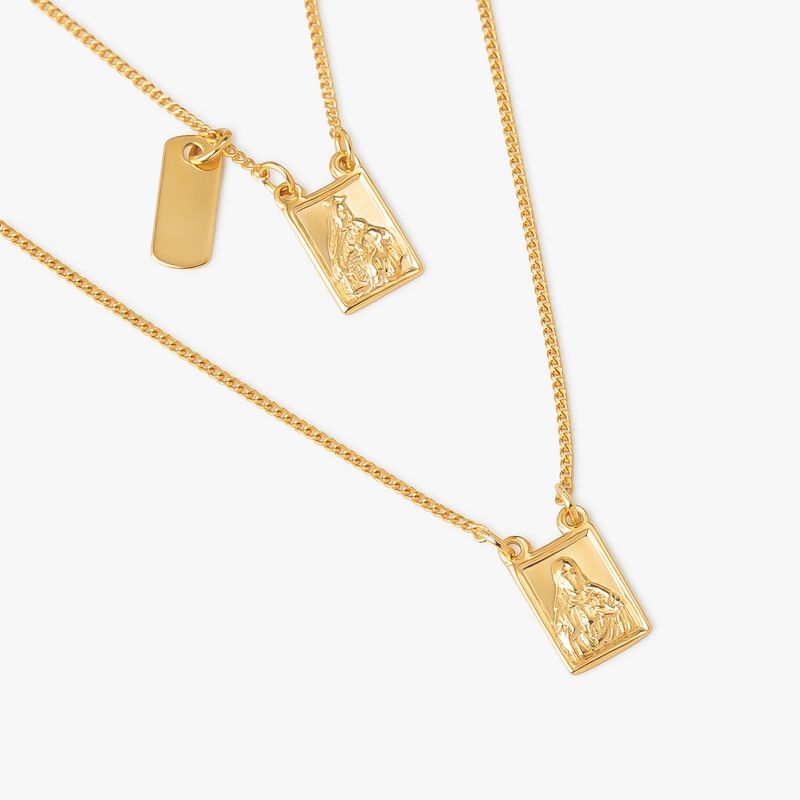 Conjunto de três colares dourados com pingentes retangulares, um com uma figura e outro com uma placa lisa.