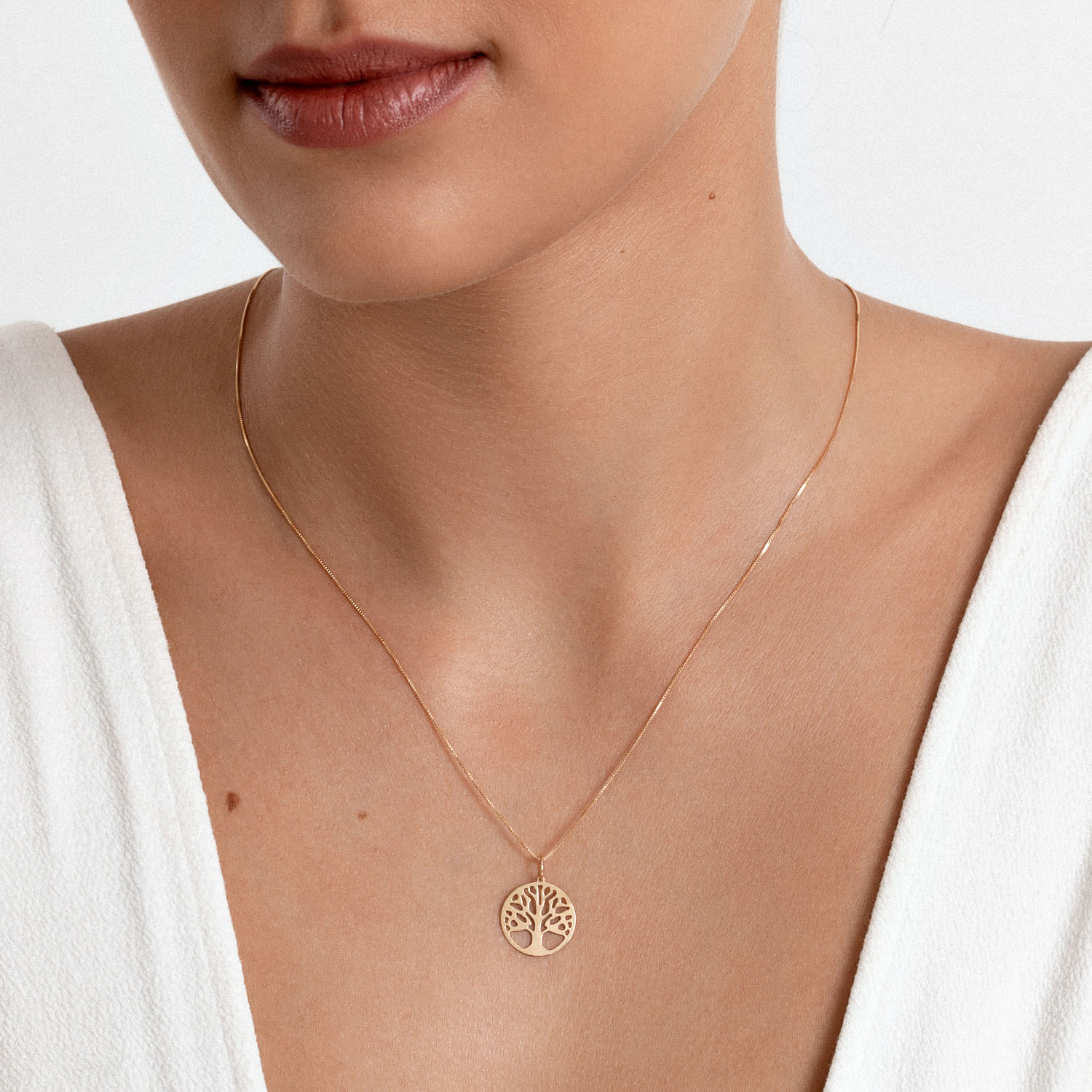 Colar dourado com pingente de árvore da vida.