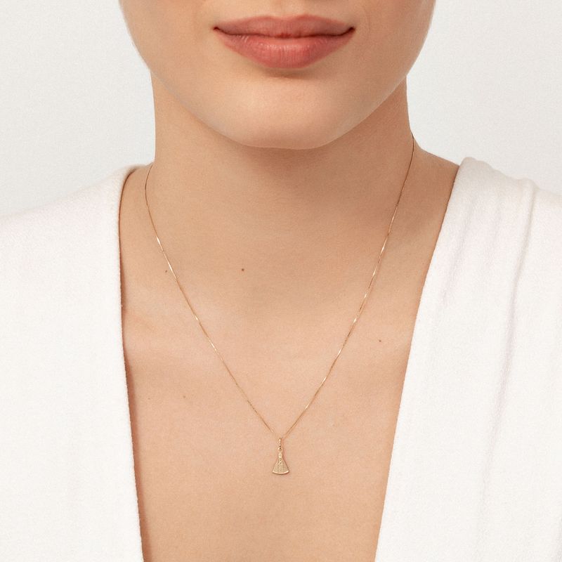 Close-up da foto de uma mulher usando um colar delicado com pingente dourado na nuca.