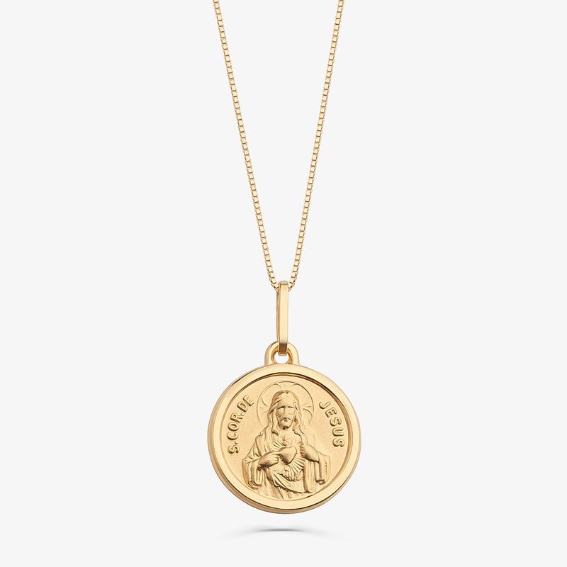 Colar dourado com medalha circular com imagem de Jesus e a inscrição "S. COR DE JESUS".