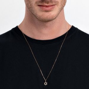 Colar com pingente de estrela de Davi em uma corrente fina, usado por um homem com camiseta preta.