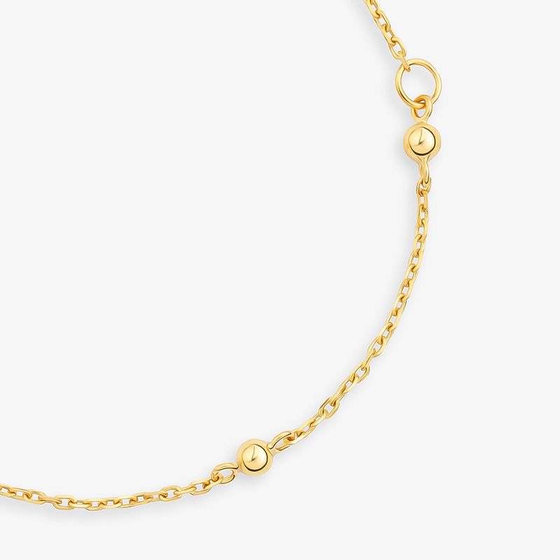 Colar dourado com corrente fina e detalhes de bolinhas arredondadas ao longo do comprimento.