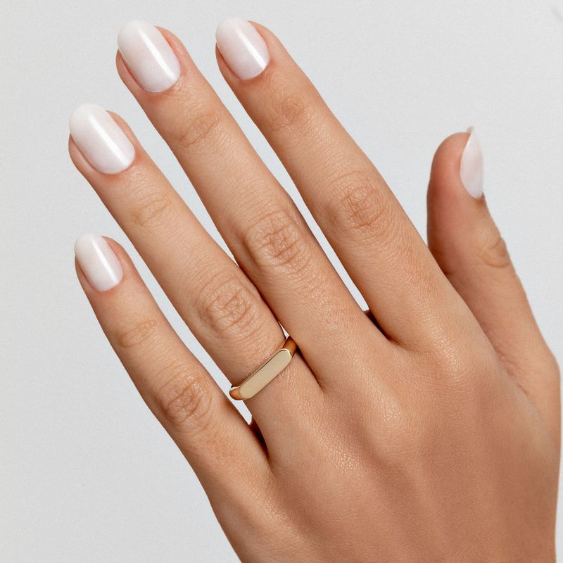 Mão com unhas pintadas de branco e uma mão com anel dourado na finger.
