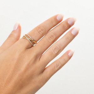 Dedo com várias alianças douradas, algumas com detalhes em pedras, sobre unhas naturally limpas e sem esmalte.