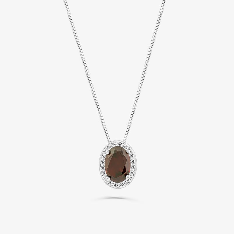 Colar com pingente oval com pedra escura rodeada de pequenas pedras cristalinas, em corrente prateada.