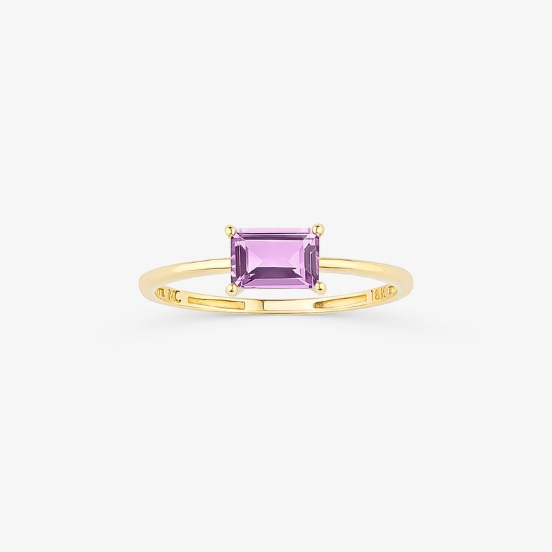 Um elegante anel de ouro com uma pedra preciosa roxa retangular cravejada em quatro garras.